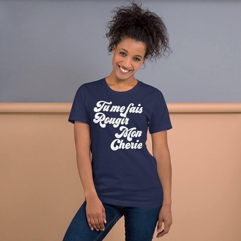 May include: A navy blue t-shirt with white text that reads "Tu me fais rougir Mon Cherie" in a retro font.