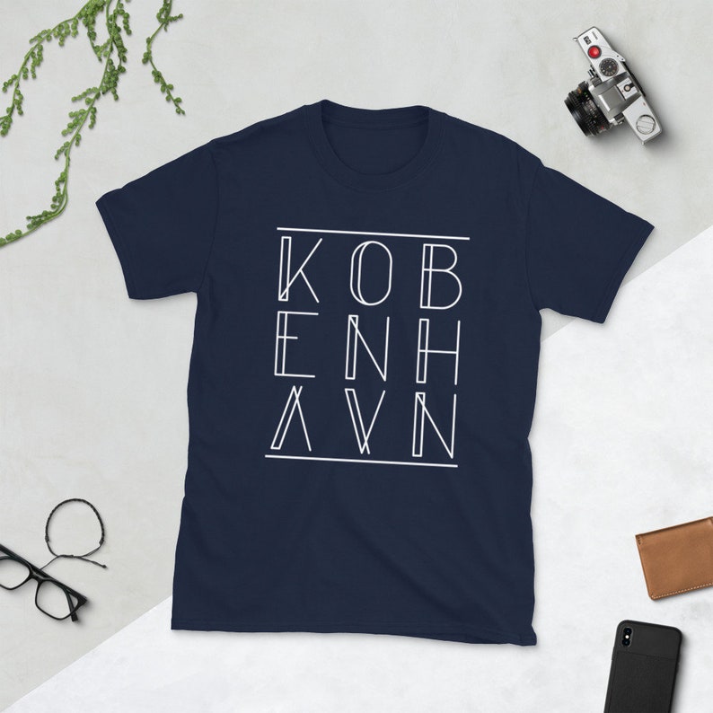 May include: A navy blue t-shirt with a white graphic design that says "KOBENHAVN" in a unique, stylized font.
