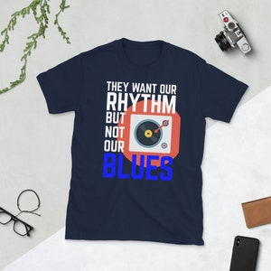 May include: Navy blue t-shirt with a white graphic of a record player and the text "They want our rhythm but not our blues".