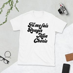 May include: White t-shirt with black text that reads "Tu me fais rougir Mon Cherie" in a retro font.
