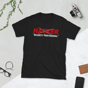Könnte beinhalten: Schwarzes T-Shirt mit rotem Text, der "HACKER" mit einem Strich durchgestrichen und darunter die Worte "SECURITY PROFESSIONAL" lautet.