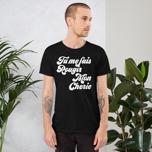 May include: Black t-shirt with white text that reads "Tu me fais rougir Mon Cherie" in a retro font.