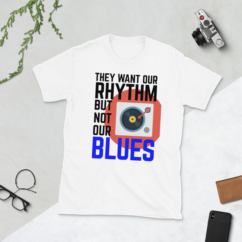 May include: White t-shirt with a red and white graphic of a record player and the text "They want our rhythm but not our blues".