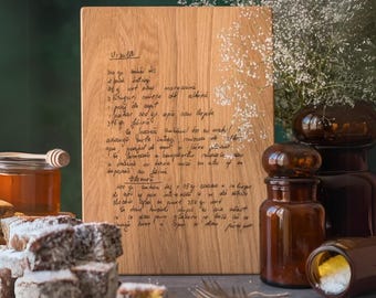 May include: A rectangular light brown wooden cutting board featuring a dark engraved handwritten recipe in Romanian. The board has a smooth grain texture and is positioned vertically, displaying detailed cooking instructions and ingredient lists.