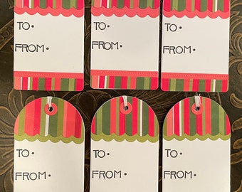 May include: Six festive gift tags with a scalloped edge and a striped pattern in red, green, and white. Each tag has a white space for "TO" and "FROM" with a string for attaching. The tags are arranged on a dark surface.