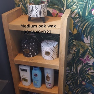 May include: A wooden shelf unit with three shelves, holding a potted plant, two decorative containers, and toiletries. The unit is 35 inches high, 16 inches wide, and 8.7 inches deep. The text "Medium oak wax" is visible.