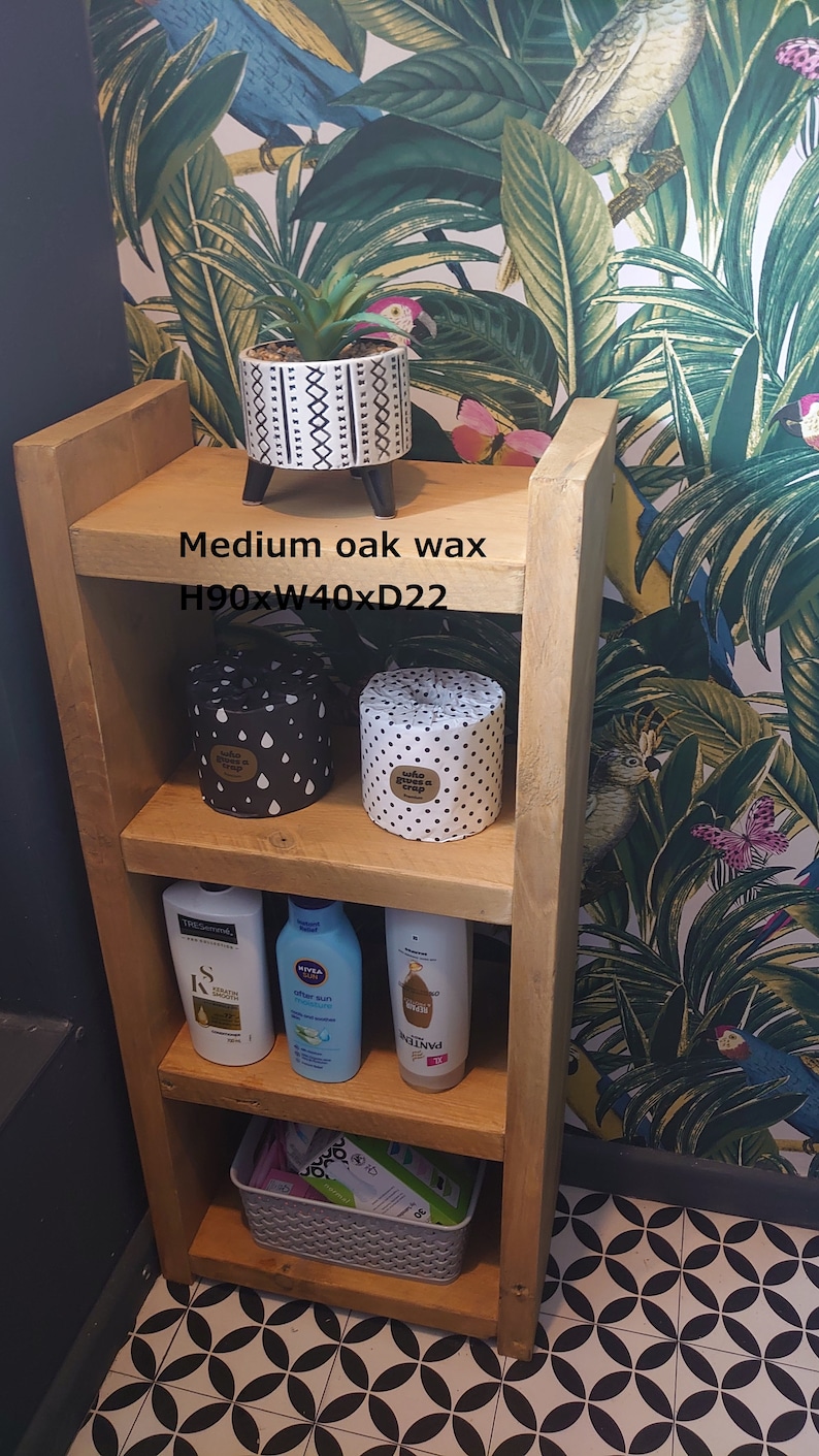 May include: A wooden shelf unit with three shelves, holding a potted plant, two decorative containers, and toiletries. The unit is 35 inches high, 16 inches wide, and 8.7 inches deep. The text "Medium oak wax" is visible.