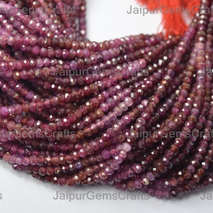 May include: A strand of deep red ruby gemstone beads, faceted and polished, with a slightly irregular shape. The beads are strung on a thread and are approximately 4 mm in diameter.