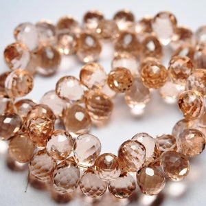 May include: A strand of faceted rose quartz beads in a light pink color. The beads are round and have a smooth, polished finish.