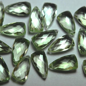 May include: A collection of 20 faceted green amethyst gemstone drops. The drops are cut in a teardrop shape and have a translucent, light green color.