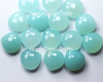 May include: A collection of 14 smooth, light blue, teardrop-shaped cabochons. The cabochons are polished and have a translucent appearance. JaipurGemsCrafts is printed on the image.