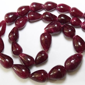 Puede incluir: Una hebra de cuentas de piedras preciosas de color rojo intenso en forma de lágrima. Las cuentas están enhebradas en un hilo transparente y están listas para ser utilizadas en la elaboración de joyas.