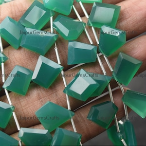 May include: A strand of green gemstone beads, each bead is faceted and has a square shape. The beads are strung on a silver wire.