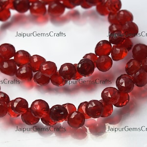Puede incluir: Una hebra de cuentas de piedras preciosas facetadas rojas. Las cuentas son redondas y tienen un acabado brillante y pulido. Las cuentas están enhebradas en un alambre delgado.