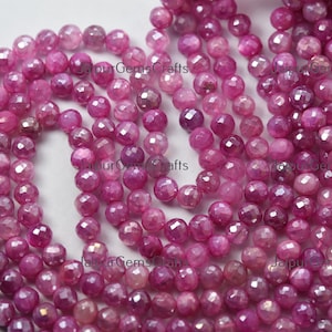 May include: A strand of pink faceted ruby beads. The beads are round and have a smooth, polished finish. The beads are strung on a clear thread.