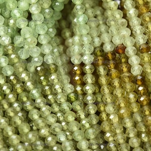 Peut inclure: Un brin de perles de pierres précieuses vertes et jaunes facettées. Les perles sont rondes et ont une finition facettées. Les perles sont enfilées sur une ficelle et sont prêtes à être utilisées pour la fabrication de bijoux.