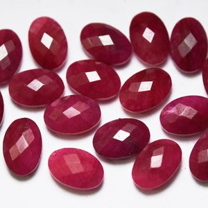 Puede incluir: Una colección de 16 piedras preciosas de rubí talladas en forma ovalada. Las piedras son de color rojo intenso y tienen un acabado pulido y brillante.