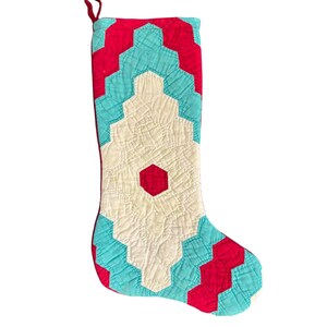May include: A red and turquoise quilted Christmas stocking with a geometric pattern.