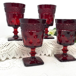 Puede incluir: Juego de cuatro copas de vidrio rojo con un patrón de diamante. Las copas tienen una base con tallo y un pie cuadrado.
