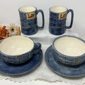 Puede incluir: Juego de café y té de cerámica de cuatro piezas. El juego incluye dos tazas y dos tazas de té con platillos. Las tazas y tazas de té están diseñadas para parecerse a los jeans de mezclilla, con la palabra "Lee" en un parche. El interior de las tazas es blanco.