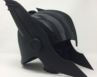 May include: A black helmet with wing-like protrusions on the sides and a ridged top. The helmet has a circular detail on the side and a pointed front. The overall design suggests a superhero or fantasy theme.