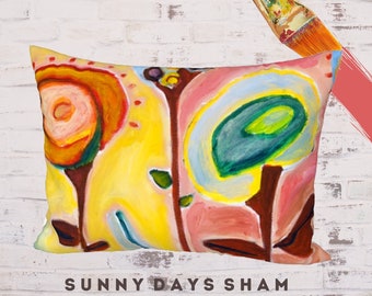 May include: A colorful pillow with a yellow background and abstract floral designs in shades of orange, pink, blue, and green. The pillow has the text "SUNNY DAYS SHAM STANDARD" printed on the bottom.