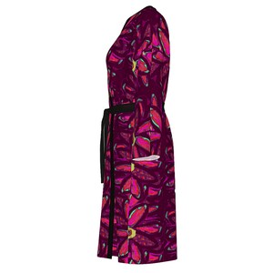May include: A long-sleeved, burgundy wrap dress with a black belt and a floral print featuring pink, green, and yellow accents.