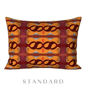 May include: A decorative pillow with a geometric pattern in shades of orange, red, and yellow. The pattern features a series of interlocking loops and swirls.