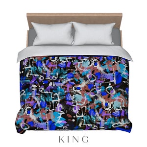 May include: A king-size bed with a duvet cover featuring an abstract design. The cover showcases a vibrant mix of blue, purple, teal, and brown brushstrokes on a black background. Two white pillows rest on the bed, with the word "KING" at the bottom.