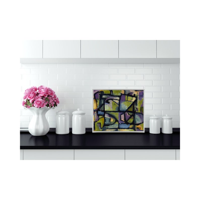 May include: Abstract painting with geometric shapes in shades of green, purple, blue, and yellow. The painting is framed in a white frame and is hanging on a white tiled wall.