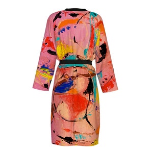 Op de afbeelding: Een roze lange, lange mouwen met een abstract print in tinten oranje, geel, blauw, groen en zwart. De robe heeft een zwarte riem.