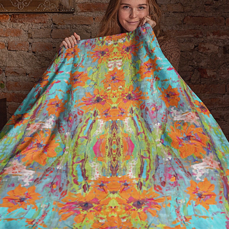 May include: A colorful abstract throw blanket with a symmetrical design featuring orange, blue, green, and pink hues. The blanket has a soft, fuzzy texture.