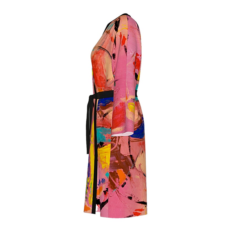 Op de afbeelding: Een lange, roze badjas met lange mouwen en een abstract print in tinten roze, geel, blauw, oranje en bruin. De badjas heeft een zwarte ceintuur.