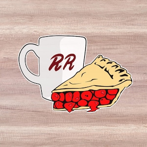 May include: A white coffee mug with the letters "RR" in red on the side, and a slice of cherry pie with a red filling and a yellow crust.