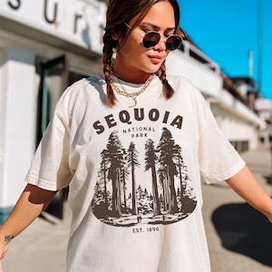 May include: Cream-colored oversized t-shirt featuring a Sequoia National Park graphic. The design includes the text "SEQUOIA NATIONAL PARK" above a brown illustration of tall trees and the text "EST. 1890".
