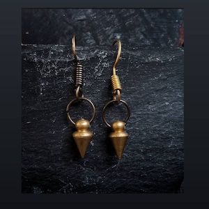 Peut inclure: Une paire de boucles d'oreilles dorées avec un design en forme de larme pointue. Les boucles d'oreilles ont une fermeture à crochet à ressort et un petit anneau doré en haut.