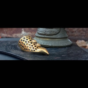 Puede incluir: Un anillo de dedo de metal de color dorado con un patrón de panal y una punta puntiaguda.