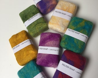 May include: Eight felted soap bars in various colors, including purple, green, yellow, teal, and red. Each bar has a white label with the text "FELTED SOAP - Little Soap Co."