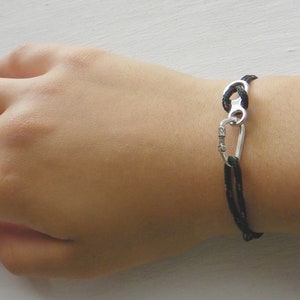 May include: A black rope bracelet with a silver carabiner clasp.