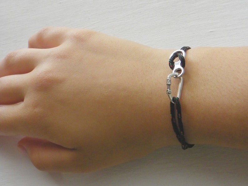 May include: A black rope bracelet with a silver carabiner clasp.