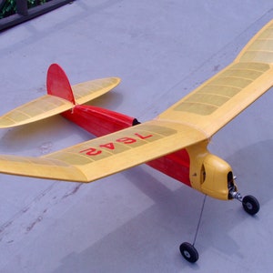 May include: A yellow and red model airplane with the number "1942" printed on the wing. The airplane has a single propeller and two wheels.