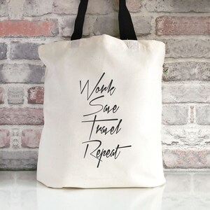 Puede incluir: Bolsa de tela blanca con asas negras y el texto "Work Save Travel Repeat" impreso en negro.