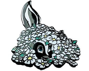 Peut inclure: Une épingle en émail noir et blanc représentant un animal de dessin animé avec une couronne de fleurs blanches. L'animal est partiellement caché par les fleurs.