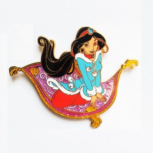 Puede incluir: Un pin de color dorado con una imagen de dibujos animados de la princesa Jasmine de Aladdin de Disney. Jasmine lleva un atuendo azul y blanco con ribete de piel y está sentada en una alfombra mágica rosa y dorada.