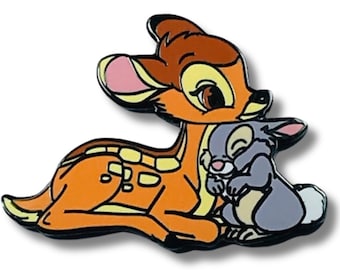 Puede incluir: Un pin de dibujos animados con Bambi el ciervo, con pelaje marrón y manchas blancas, acostado y abrazando a Thumper el conejo, que es gris con una cola blanca y una nariz rosa.