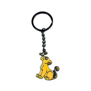 May include: Black metal keychain featuring a cartoon lion cub with a yellow body and black tail, looking up at a butterfly.