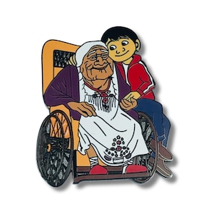 May include: A colorful enamel pin featuring characters from the animated movie Coco. The pin depicts an elderly woman in a wheelchair with a young boy embracing her. The pin has a white background.