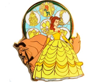 Op de afbeelding: Een gouden emaille pin met Belle uit Disney's Belle en het Beest. Belle draagt haar iconische gele baljurk en staat voor een gebrandschilderd raam met afbeeldingen van de betoverde voorwerpen uit de film.