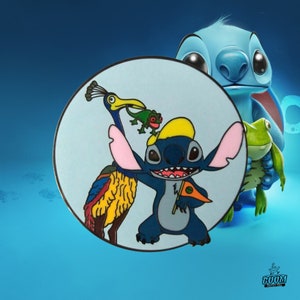 May include: A round, light blue pin featuring Stitch from Lilo & Stitch, wearing a yellow hat and holding a flag. The pin also includes a bird and a frog. The background is a gradient of blue.