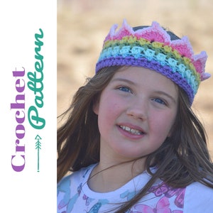 May include: A young girl wearing a colorful crocheted crown headband. The headband is made with a rainbow of colors, including pink, yellow, green, blue, and purple.